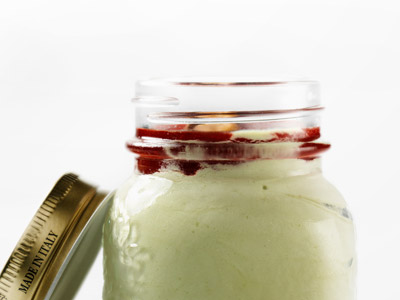 Pistazien-Expresseis mit Himbeersauce und ganzen Pistazien.